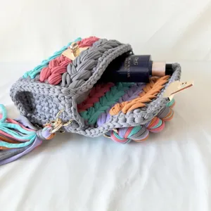 Detail view of handmade rainbow crochet crossbody bag showing colorful fabric knit texture and lock.
