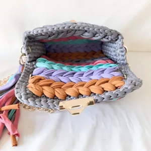 Handmade crochet t-shirt yarn crossbody bag detail with colorful interior stripes.