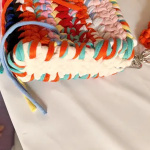 Close-up detail of colorful woven fabric shoulder bag, showing handmade crochet texture.