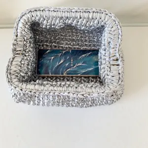 Silver crochet clutch bag interior detail, handmade fabric woven texture close up.