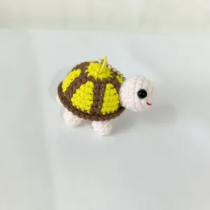 Vue détaillée du porte-clés tortue au crochet fait main, montrant une texture de fil fine et jolie.
