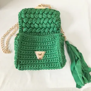 Handmade green crochet crossbody bag with gold chain and stylish tassel pendant detail.