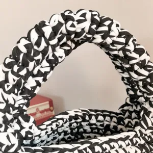 Close-up detail view of black and white handmade crochet bag handle featuring chunky knit texture.