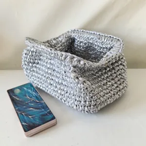 Silver metallic crochet clutch bag detail, handmade fabric yarn woven texture handbag close-up.