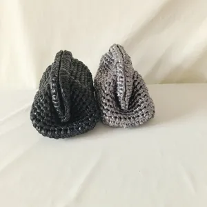 Close-up detail of handmade crochet clutch bags in black and silver, woven cloth texture.