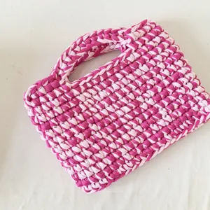 Handcrafted crochet fabric strip handbag detail shot, pink and white color block design chic.