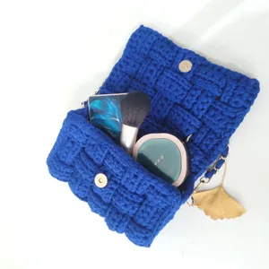 Handmade crochet blue crossbody bag with chain strap and elegant ginkgo leaf charm detail.