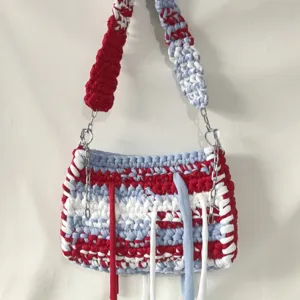 Handcrafted crochet t-shirt yarn shoulder bag with colorful stripes and fringe details.