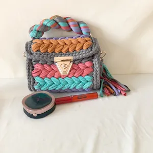 Handmade crochet shoulder bag with colorful braided handles and stylish tassel detail.
