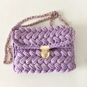 Handmade purple crochet fabric crossbody bag detail, showing fine woven texture and gold chain.