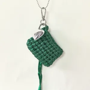Handmade dark green woven earphone bag with silver heart charm and chain detail closeup.