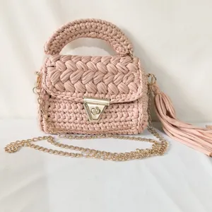 Handmade crochet shoulder bag detail, pink fabric strip weave texture with gold chain.