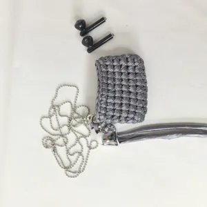 Detailed shot of handmade silver woven earphone case with metal chain and heart charm.