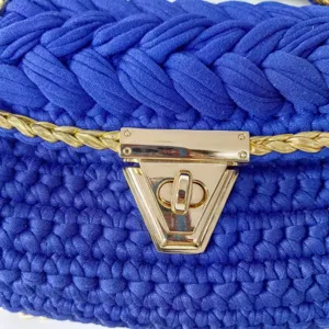 Close-up detail of royal blue handmade crochet fabric yarn handbag with gold metal lock.