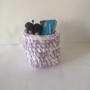 Détail de panier de rangement de maquillage au crochet fait main en fil tricoté violet.