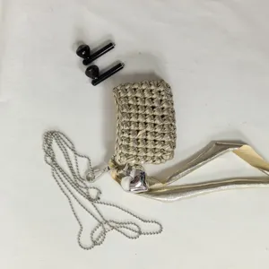 Handmade woven earphone bag detail view, showing metallic gold texture, heart pendant and chain.