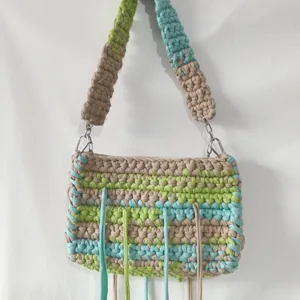 Handmade crochet t-shirt yarn shoulder bag detail, colorful knit stripe design with cute fringe.
