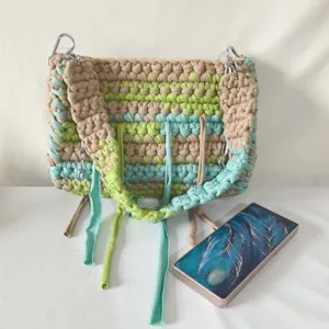 Handmade crochet woven shoulder bag for women with wide straps, colorful fabric strips and fringe.