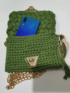Handmade green crochet phone bag with gold chain strap and stylish tassel charm accessory.