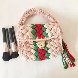 Chunky crochet woven handbag detail shot, green and red striped design with metal lock closure.