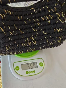 Handgemachte schwarze Strick-Clutch Detailansicht, Goldfaden Textur, leichtes Design Nahaufnahme.