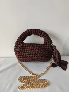 Close-up detail of handmade brown woven crossbody bag with golden chain and tassel.
