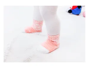 Gedetailleerde close-up van zachte katoenen babysokken met schattig roze ruitjespatroon.