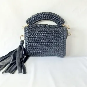 Detailed view of black handmade crochet mini square bag with chunky handle and stylish tassel accent.