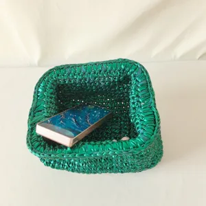 Handmade metallic green crochet clutch bag detail showing exquisite woven fabric texture.