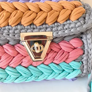 Close-up detail of handmade colorful crochet shoulder bag with vibrant fabric yarn and gold lock.