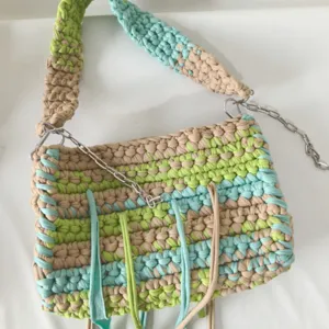 Handmade crochet crossbody bag detail showing fabric texture and metal chain strap.