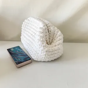 Detailed view of the white handmade crochet clutch bag, showing the thick yarn weave texture.