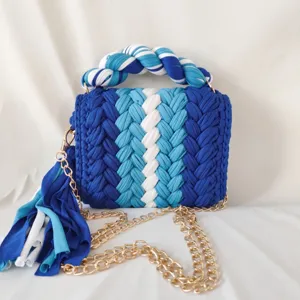 Close-up detail of handmade color-block crocheted handbag, showing textured braid and chain strap.