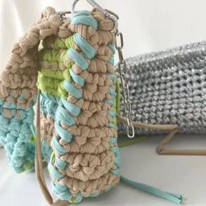 Handmade crochet shoulder bag with colorful t-shirt yarn and chic metal chain strap details.