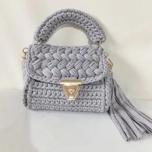 Detailed view of the handmade grey crochet shoulder bag featuring a chic side tassel and lock.
