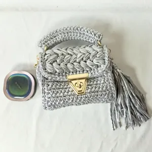Closeup view of the metallic crochet shoulder bag, silver woven texture with chic tassel.
