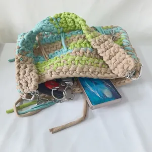 Handmade crochet knit bag detail showing colorful striped fabric and wide strap.