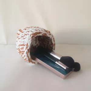 Vue détaillée du panier de rangement de maquillage au crochet, tressé blanc et marron.