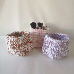 Gros plan de paniers de rangement au crochet faits main en marron, rose et violet.