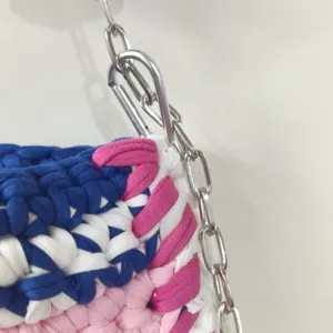 Handcrafted crochet fabric bag detail showcasing intricate blue white pink knit texture and chain link.