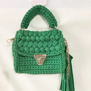 Handmade green crochet shoulder bag with gold turn-lock closure and chic tassel charm.