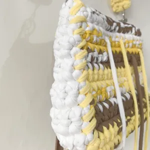 Close-up detail of handmade crochet fabric strip shoulder bag with multi-color striped design.