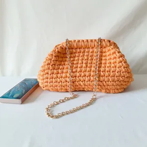 Handmade crochet clutch bag detail showing textured orange fabric and gold chain strap.
