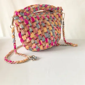 Nahaufnahme Detail der handgearbeiteten bunten Häkeltasche mit geflochtener Textur und Kette.
