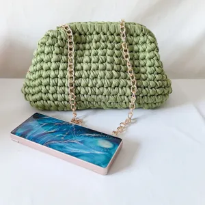 Handmade green crochet clutch bag with gold chain strap and stylish blue hard case cover.