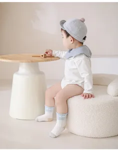 Vista dettagliata di comodi calzini in cotone per neonati indossati da un bambino su un poggiapiedi.