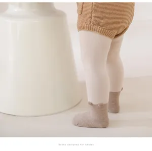 Detalle de leggings y calcetines de punto para bebé, material suave, tonos beige y marrón claro.