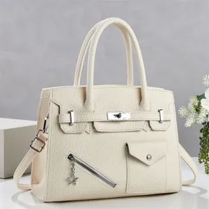 Détail élégant de sac à main beige pour femme avec design structuré, fermoir en métal et fermeture.