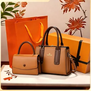 Detail view of stylish brown leather handbag set with top handles and shoulder strap.