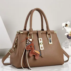 Vista detallada del elegante bolso de cuero marrón con herrajes dorados y un bonito abalorio.